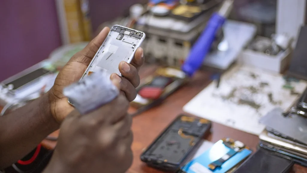 Persona reparando un teléfono móvil sobre una mesa de trabajo